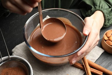 Siyah masada çikolata hamuru kepçesi alan kadın, yakın plan.