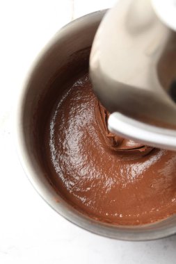 Beyaz masada kasede çikolata hamuru karıştırmak, üst manzara.
