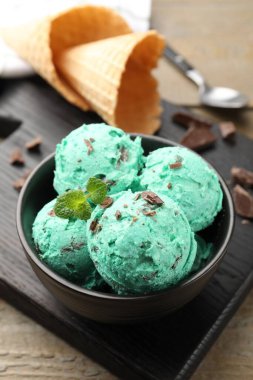 Çikolata parçalı lezzetli dondurma ve waffle külahları ahşap masada, yakın plan.