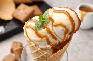 Karamel soslu lezzetli dondurma ve gri masada nane şekeri, yakın plan.