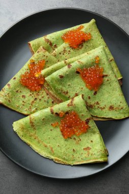 Gri masadaki kırmızı havyarlı lezzetli ıspanaklı krep.