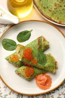 Tahta masada servis edilen somon, avokado ve kırmızı havyarlı ıspanaklı krep.