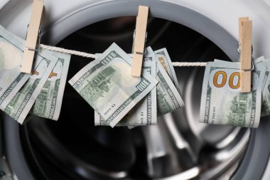 Çamaşır makinesinin yanındaki çamaşır ipinde asılı banknotlar.