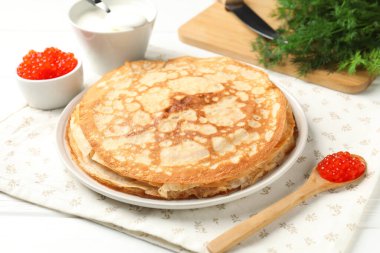 Kırmızı havyarlı lezzetli krepler, ekşi krema ve beyaz ahşap masada dereotu, yakın plan.