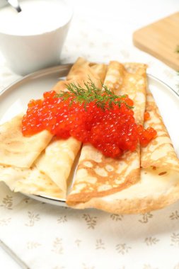 Kırmızı havyarlı lezzetli krepler, ekşi krema ve dereotlu masa, yakın plan.