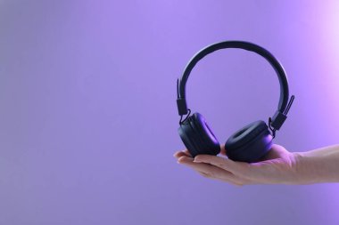 Violet Gradient arka planında şık kulaklıklı bir kadın, yakın plan. Metin için boşluk