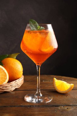 Bir bardak ferahlatıcı spritzer kokteyli. Nane ve portakallar ahşap masada.