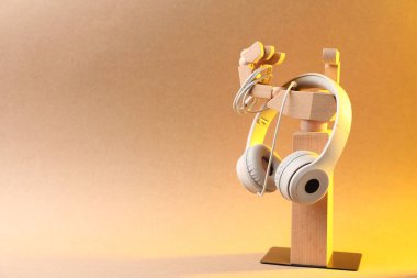 Sarı ışıkta bej arka planda şık kulaklıklı manken eli. Metin için boşluk