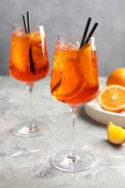 Gri desenli masaya serinletici spritzer kokteyli ve portakallar.