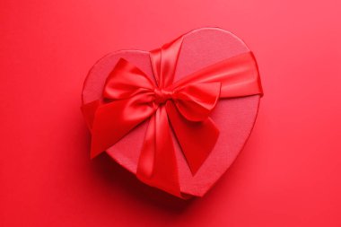 Sevgililer Günün kutlu olsun. Kırmızı arkaplanda kalp şeklinde hediye kutusu, üst görünüm