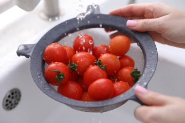 Lavaboda vişneli domatesleri elek ile yıkayan kadın, yakın plan.