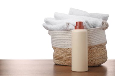 Çamaşır sepetinde havlular ve bir şişe deterjan beyaz arka plana karşı ahşap masada.