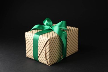 Siyah arka planda güzel paketlenmiş hediye kutusu, yakın plan.