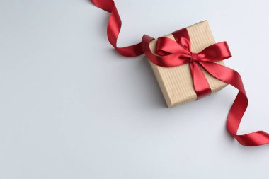 Işık arkaplanda güzel kırmızı kurdeleli hediye kutusu, üst manzara. Metin için boşluk