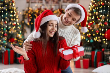 Mutlu erkek arkadaşı evde Noel hediyesiyle kız arkadaşına sürpriz yapıyor.