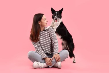 Pembe arka planda sevimli Sınır Köpeği Collie köpeği olan bir kadın.