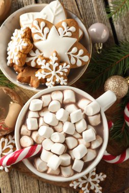 Lezzetli kakao, şekerlemeler, baston şekerler, zencefilli kurabiyeler ve Noel süslemeleri ahşap masada, düz uzanmış