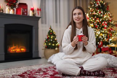 Bir fincan sıcak kakaolu ergen kız. Odada marşmelov var. Noel için dekore edilmiş.