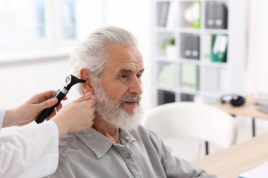 Duyma testi. Klinikte otoskopla hastanın kulağını muayene eden doktor, yakın plan. Metin için boşluk