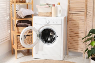 Çamaşır sepetinin içinde havlular ve çamaşır makinesinin üzerindeki deterjan şişeleri.