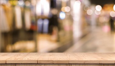 Boş ahşap masa, bulanık alışveriş merkezi manzarasına karşı. Tasarım için boşluk