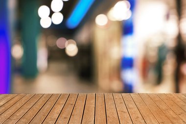 Boş ahşap masa, bulanık alışveriş merkezi manzarasına karşı. Tasarım için boşluk