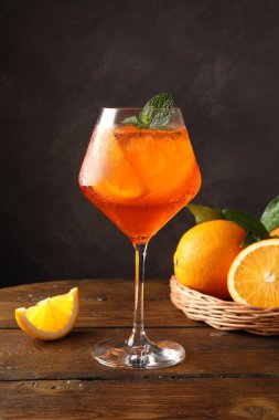 Bir bardak ferahlatıcı spritzer kokteyli. Nane ve portakallar ahşap masada.