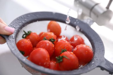 Lavaboda vişneli domatesleri elek ile yıkayan kadın, yakın plan.