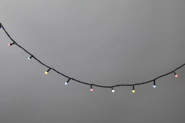 Gri arka planda parlak Noel ışıkları, yakın plan