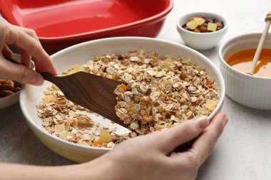 Tahıl yapıyorum. Bir kase yulaf lapası, bal ve kuru meyveli kadın açık gri masada, yakın plan.