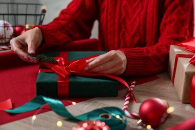 Noel hediyesini ahşap masaya paketleyen kadın, yakın plan.