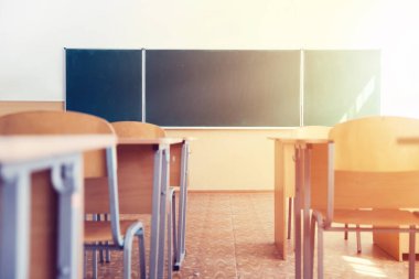 Güneşli bir günde kurul, sandalye ve masalarla dolu bir sınıf seçici bir odak noktası.