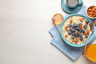 Kuru yulaf, fındık ve yaban mersini kahvaltıda gri ahşap masada servis edilir. Metin için boşluk