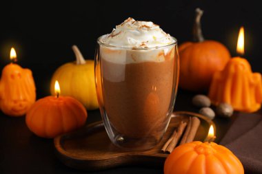 Krem şantili balkabaklı latte ve siyah arka planda sonbahar dekoru, yakın plan.