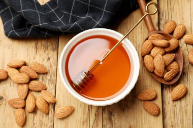 Lezzetli bal kasede, kepçede, kaşıkta ve bademlerde ahşap masada, düz yerde.