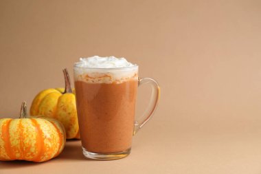 Cam bardakta kremalı balkabaklı latte ve bej arka planda taze sebzeler, yakın plan. Metin için boşluk