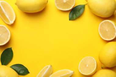 Taze olgun limonlardan yapılmış çerçeve ve sarı arka plandaki yapraklar düz. Metin için boşluk
