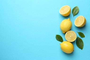 Taze limonlar ve açık mavi arka planda yapraklar, düz. Metin için boşluk