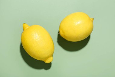 Açık yeşil zemin üzerinde taze olgun limonlar, düz uzanmış