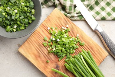 Açık gri masada yeşil soğan ve bıçak kes, düz yat.