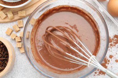 Kasede çırpılmış çikolata hamuru ve gri desenli masada baharatlar.