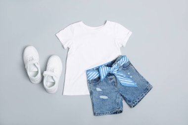 Şık çocuk kıyafetleri ve hafif arka planda ayakkabılar, düz yatış.