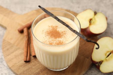 Lezzetli protein karışımı cam, elma, tarçın ve vanilya kapsülleri gri masada, yakın plan