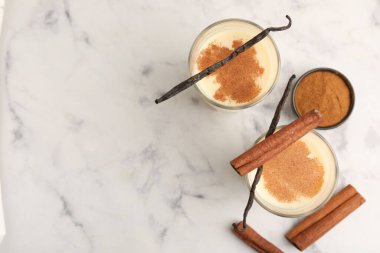 Lezzetli protein karışımı bardaklarda, tarçınlı ve vanilyalı kapsüller beyaz mermer masada, düz yerde. Metin için boşluk