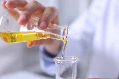 Bilim adamı laboratuarda motor yağını şişeye boşaltıyor.