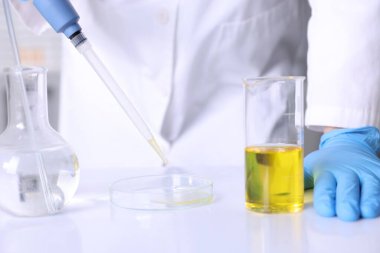 Laboratuvarda, Petri kabına motor yağı damlatan bir bilim adamı.