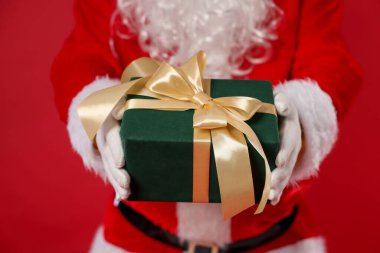Kırmızı arka planda Noel hediyesi olan Noel Baba, yakın plan.