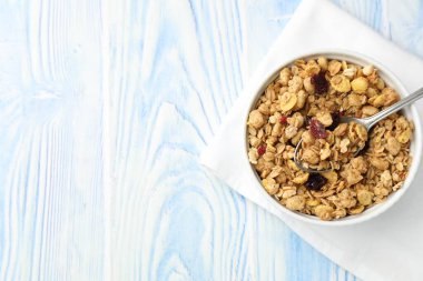 Açık mavi ahşap masada kurumuş meyveli leziz granola, üst manzara. Metin için boşluk