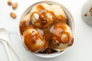 Karamel soslu lezzetli dondurma, badem ve beyaz masada patlamış mısır.