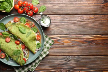 Lezzetli ıspanaklı krep, domates, soğan, ekşi krema ve ahşap masa üzerinde yapraklar, düz yatak. Metin için boşluk